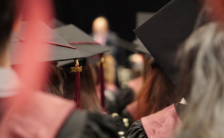 Cap and gown students listening to commencement speech